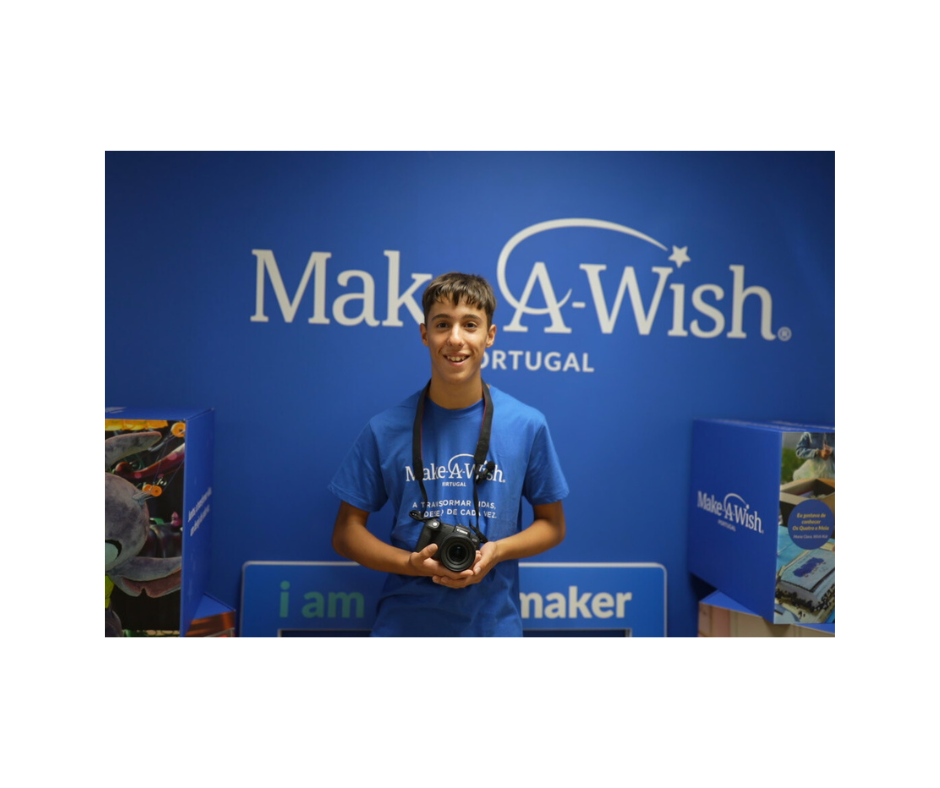 O Rafael segura a sua nova máquina fotográfica no escritório da Make-A-Wish.